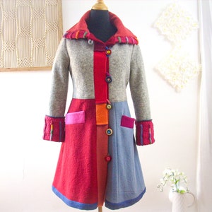 Puede incluir: Una colorida chaqueta de patchwork con capucha, con una combinación de colores grises, rojos, naranjas y azules. La chaqueta tiene cierre de botones y bolsillos a los lados.
