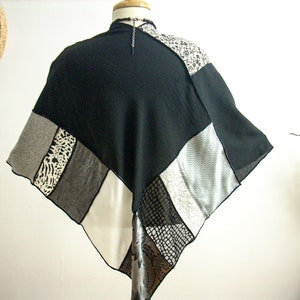 K&ouml;nnte beinhalten: Ein schwarzer, wei&szlig;er und grauer Patchwork-Poncho mit geometrischem Muster. Der Poncho besteht aus verschiedenen Stoffen, darunter ein durchsichtiger Stoff, ein Strickstoff und ein gewebter Stoff.
