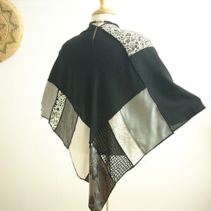 K&ouml;nnte beinhalten: Ein schwarz-wei&szlig;es Patchwork-Poncho mit geometrischem Muster. Das Poncho besteht aus verschiedenen Stoffen, darunter durchsichtige und strukturierte Materialien.