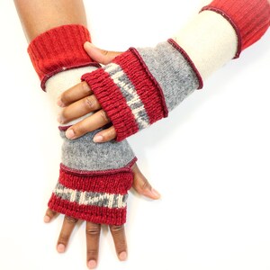 May include: A pair of knitted fingerless gloves in red, gray, and cream colors. The gloves have a ribbed cuff and a patterned design on the wrist. The gloves are made of a soft, warm material, perfect for cold weather.
