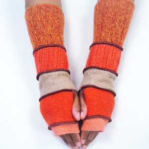 May include: A pair of orange, brown, and beige fingerless gloves with a knitted design.