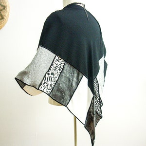 K&ouml;nnte beinhalten: Schwarz-wei&szlig;es Patchwork-Poncho mit geometrischem Muster. Das Poncho besteht aus verschiedenen Stoffen, darunter ein schwarzer Strickstoff, ein grauer Strickstoff, ein wei&szlig;er Stoff mit schwarzem Druck und ein wei&szlig;er Stoff mit einem schwarz-wei&szlig;en Tierdruck.