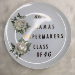 May include: White ceramic plate with gold lettering that reads "40th Anniversary", "Camas Papermakers", "Class of 46". The plate is decorated with two white roses with pink centers.