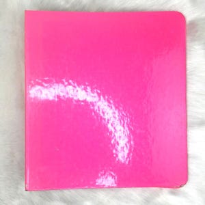 May include: A bright pink binder with a glossy finish.