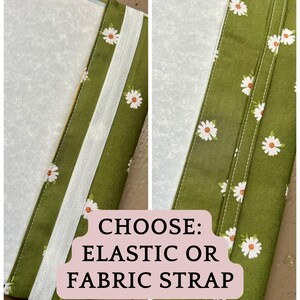 Puede incluir: Una funda de tela verde con un patr&oacute;n de margaritas blancas, mostrada con dos opciones de cierre: una banda el&aacute;stica blanca a la izquierda y una correa de tela verde a juego a la derecha. El texto CHOOSE: ELASTIC OR FABRIC STRAP est&aacute; centrado.