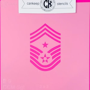 May include: Pink plastic stencil of the United States Air Force E-9 Chief Master Sergeant rank insignia. The stencil is 2 inches by 3 inches and includes the text "E-9 CCM Sgt".