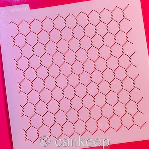 May include: A white plastic stencil with a repeating pattern of a wire fence. The stencil is designed for use with paint, icing, or other mediums to create a decorative effect.