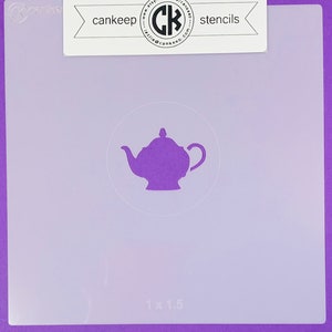 May include: Purple plastic stencil of a teapot with a 1 x 1.5 inch measurement. The stencil is for crafting and decorating.