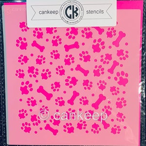 May include: Pink plastic stencil with a repeating pattern of paw prints and bones. The stencil is packaged in a clear plastic sleeve and has the text "cankeep stencils" printed on the top.