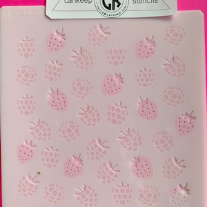 May include: A white plastic stencil with a pink background featuring a repeating pattern of strawberries and raspberries. The stencil is labeled "cankeep stencils" and includes the website address "www.cankeep.com".