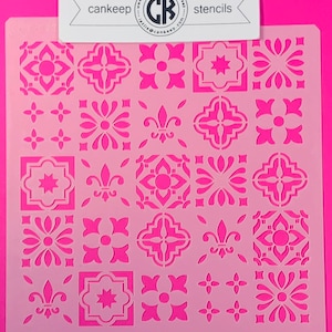 May include: A white plastic stencil featuring a repeating pattern of 25 different tile designs. The designs include stars, flowers, and fleur-de-lis. The stencil is designed for use with paint or other mediums to create a decorative tile effect.