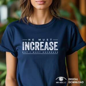 Może przedstawiać: Koszulka w kolorze granatowym z białym napisem "On musi zwiększyć, ale ja muszę zmniejszyć".