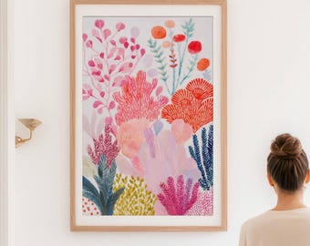 Könnte beinhalten: Ein gerahmter Aquarelldruck mit floralem Motiv in einem hellen Holzrahmen. Das Kunstwerk zeigt eine farbenfrohe Anordnung von rosa, orangefarbenen und blauen Blumen und Blättern. Der Druck befindet sich an einer weißen Wand in einem Badezimmer.