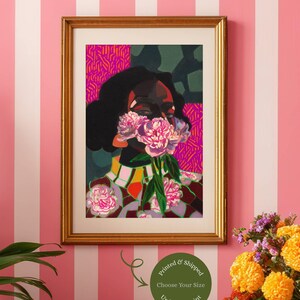 May include: A framed art print featuring a stylized portrait of a person with dark skin, holding a cluster of pink peonies over their face. The artwork uses vibrant colors, including magenta, orange, and deep green, with a patterned background.