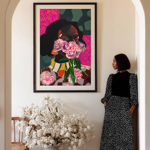 May include: A framed rectangular wall art print featuring a stylized portrait of a person with dark hair, partially obscured by a cluster of pink peony flowers. The background includes vibrant magenta and dark green geometric patterns.