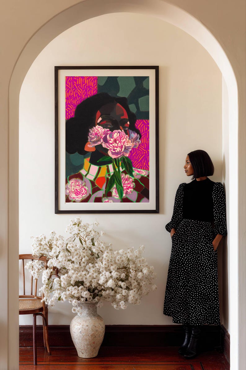 May include: A framed rectangular wall art print featuring a stylized portrait of a person with dark hair, partially obscured by a cluster of pink peony flowers. The background includes vibrant magenta and dark green geometric patterns.