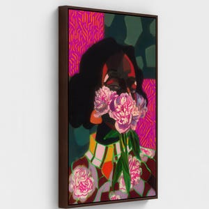 May include: A vertical rectangular canvas print titled Walnut Framed Canvas, featuring a stylized portrait of a figure with dark skin, obscured by a bouquet of pink peonies. The background displays vibrant magenta and dark green geometric patterns.
