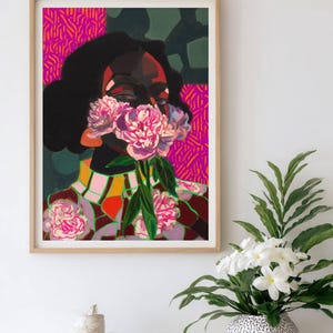 May include: A framed art print featuring a stylized portrait of a person with dark hair, their face partially obscured by a cluster of pink peony flowers. The background consists of vibrant magenta and dark green geometric patterns and shapes.