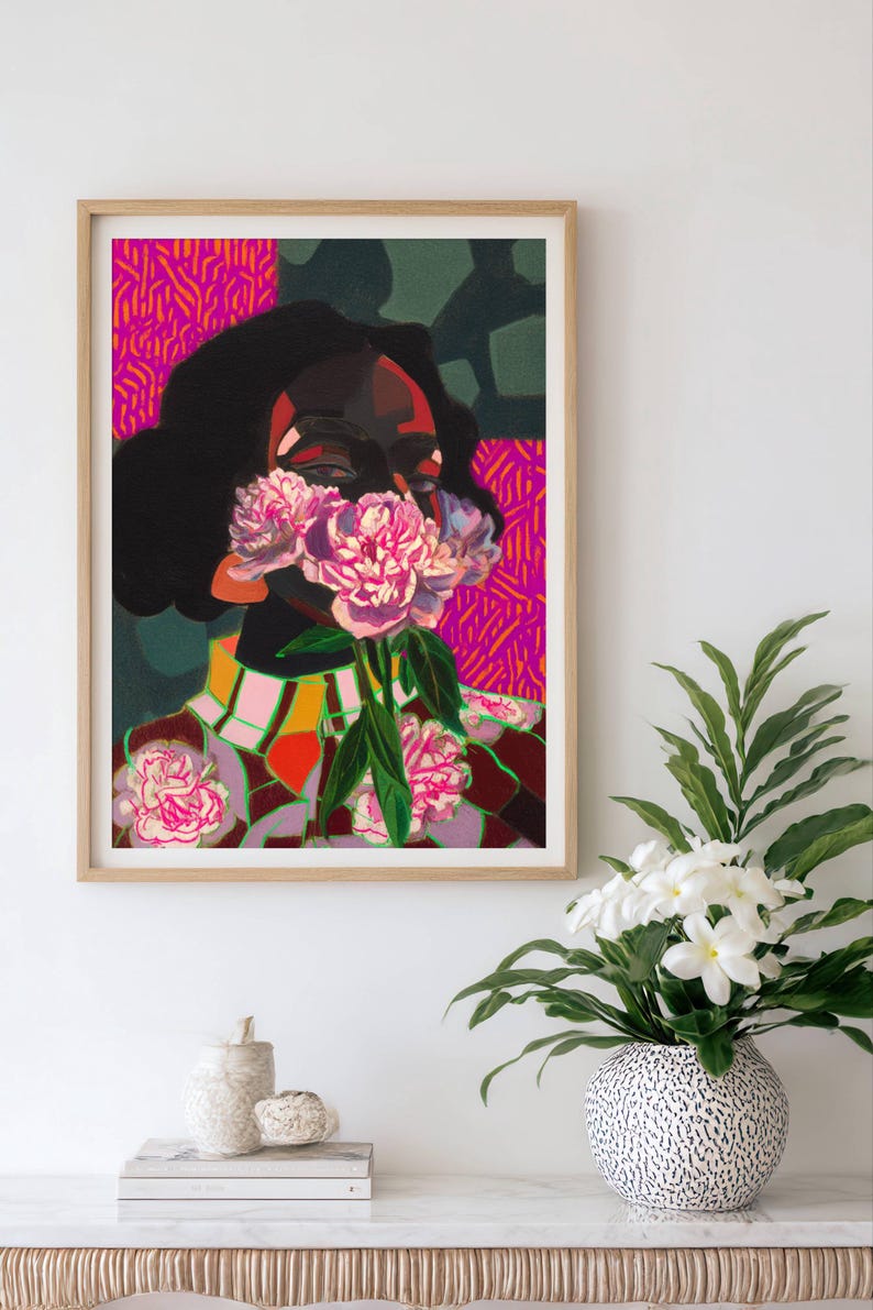 May include: A framed art print featuring a stylized portrait of a person with dark hair, their face partially obscured by a cluster of pink peony flowers. The background consists of vibrant magenta and dark green geometric patterns and shapes.
