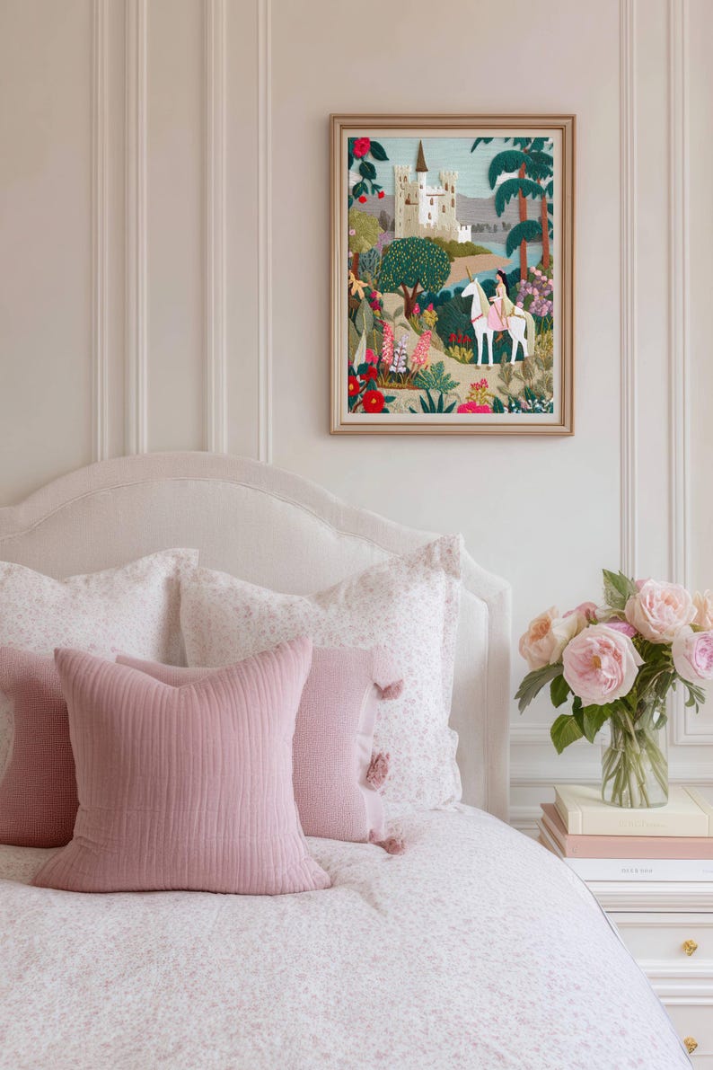 May include: A framed textile art piece featuring an embroidered scene of a white castle, a person riding a white unicorn, and colorful floral landscapes with green trees. The artwork is displayed in a light-colored wooden frame.