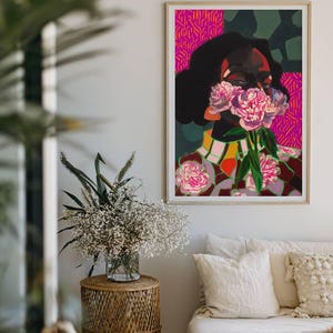 May include: A framed rectangular art print featuring a stylized portrait of a person with dark skin and hair, holding pink peony flowers over their face. The background consists of vibrant magenta and dark green geometric patterns.