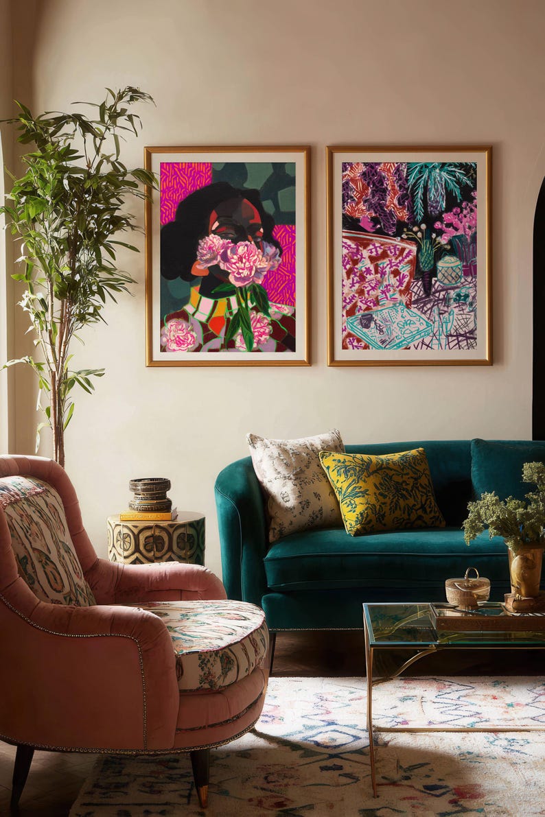 May include: Two framed rectangular art prints hanging side by side. The left print features a person holding pink flowers over their face with a vibrant pink and green background. The right print displays a colorful, abstract interior scene with plants.