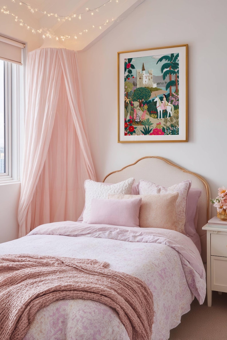 May include: A bedroom with a pink and gold theme. The bed has a light pink comforter, pillows, and a knitted throw. A framed picture with a castle scene hangs above the bed. A pink canopy and string lights add to the decor.