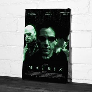 May include: A canvas print of "The Matrix" film poster. The poster features Laurence Fishburne, Keanu Reeves, and Carrie-Anne Moss. The title "MATRIX" is in green, with a green digital rain effect. The background is black.