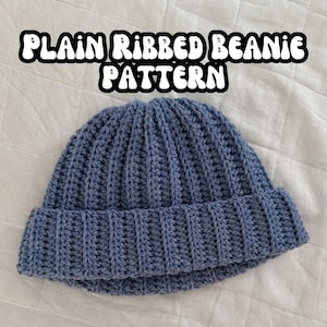 Op de afbeelding: Een blauwe gebreide beanie met een geribbeld patroon. De beanie is omgeslagen aan de rand. De tekst "PLAIN RIBBED BEANIE PATTERN" staat in witte letters op een witte achtergrond.