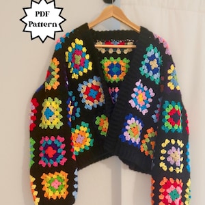 Könnte beinhalten: Schwarze Häkeljacke mit bunten Granny Squares. Die Jacke hängt an einem Holzbügel. Der Text "PDF Pattern" befindet sich in einer weißen Sternform.