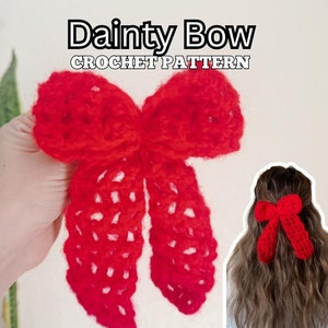 May include: A bright red crochet bow with long, dangling tails featuring an open-work stitch pattern. The text "Dainty Bow CROCHET PATTERN" is displayed at the top. A smaller inset shows the red bow worn in wavy hair.