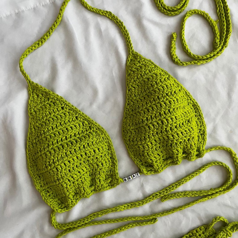 May include: Lime green crochet bikini top with adjustable straps and a "BRAT" charm.