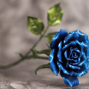 以下が含まれることがあります： 緑の葉が付いた青い金属製のバラ1本。バラは金属製で光沢のある仕上げです。