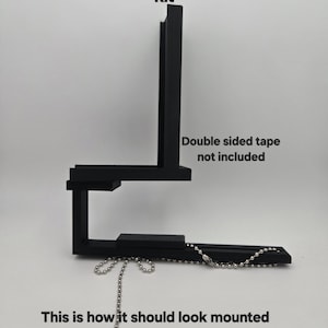 May include: Black Universal focal Stick Eliminator kit. The kit is shown mounted with a chain. The text on the image says, "Double sided tape not included" and "This is how it should look mounted on your loaser. simply add double sided tape and set your length."