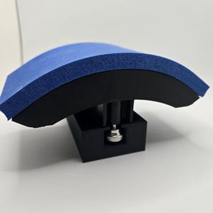May include: A blue and black foam sanding block with an adjustable knob. The block is curved and designed for sanding curved surfaces.