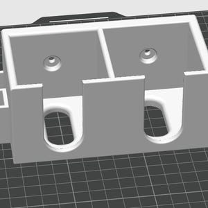 May include: A white plastic 3D printed storage organiser with two compartments and three slots. The organiser has a textured surface.