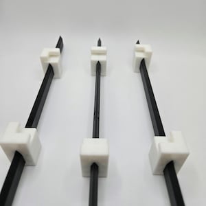 May include: Three black metal rods with white plastic connectors at each end. The rods are arranged in a row, with the connectors facing the viewer.