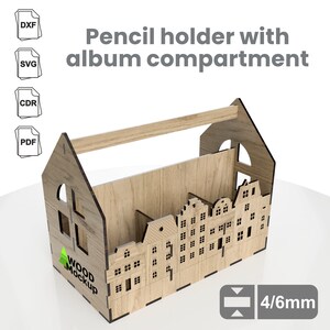 May include: Wooden pencil holder with a built-in album compartment. The holder is shaped like a house with a handle on top. The front of the holder features a design of small houses. The text "WOOD MOCKUP" is printed on the side of the holder. The holder is 4/6mm thick.