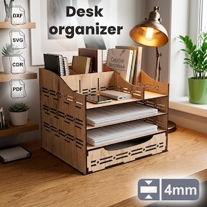 May include: A light-colored wooden desk organizer featuring multiple tiers for paper storage, a top section for notebooks, and a bottom drawer. The structure has laser-cut geometric patterns on the sides and is designed for 4mm thick material.