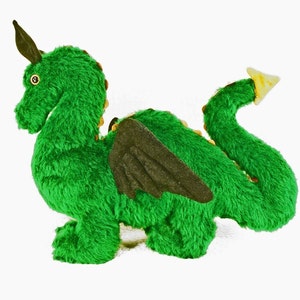 May include: Green plush dragon toy with black wings and a gold-colored horn. The dragon is curled up in a playful pose.