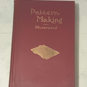 May include: A maroon book titled "Pattern Making Illustrated" with gold lettering and a gold embossed design. The book is slightly angled, showing its cover and spine.
