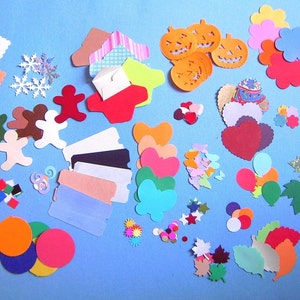May include: A collection of colorful paper cutouts in various shapes, including gingerbread men, pumpkins, hearts, leaves, and circles. The cutouts are in shades of red, orange, green, yellow, and blue, perfect for crafting and scrapbooking projects.