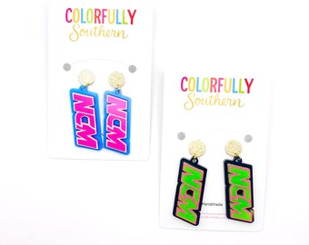 May include: Two pairs of dangle earrings on white display cards labeled Colorfully Southern. One pair features blue rectangular charms with pink text reading NCM and gold glitter studs. The other pair has black charms with green text reading NCM.