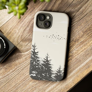 May include: A beige phone case with a black silhouette of a forest and a flock of birds flying overhead.