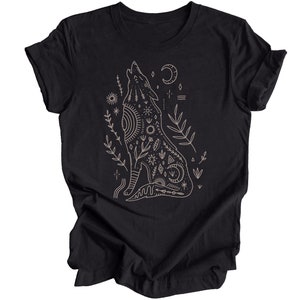 May include: Black t-shirt with a line drawing of a wolf howling at the moon. The wolf is surrounded by flowers and other nature-inspired designs.