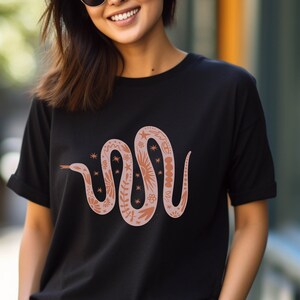 May include: A black t-shirt with a brown snake design. The snake is decorated with floral and star patterns.