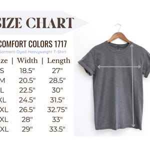 May include: A gray Comfort Colors 1717 heavyweight t-shirt hangs on a wooden hanger. The image includes a size chart with measurements in inches for sizes S through 4XL. The text "SIZE CHART" is at the top.
