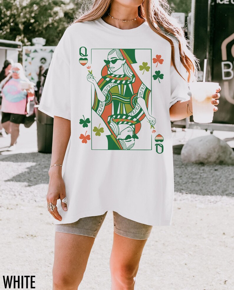 May include: White oversized t-shirt featuring a graphic print of a queen of hearts playing card with shamrocks. The queen is wearing sunglasses and holding a flower.