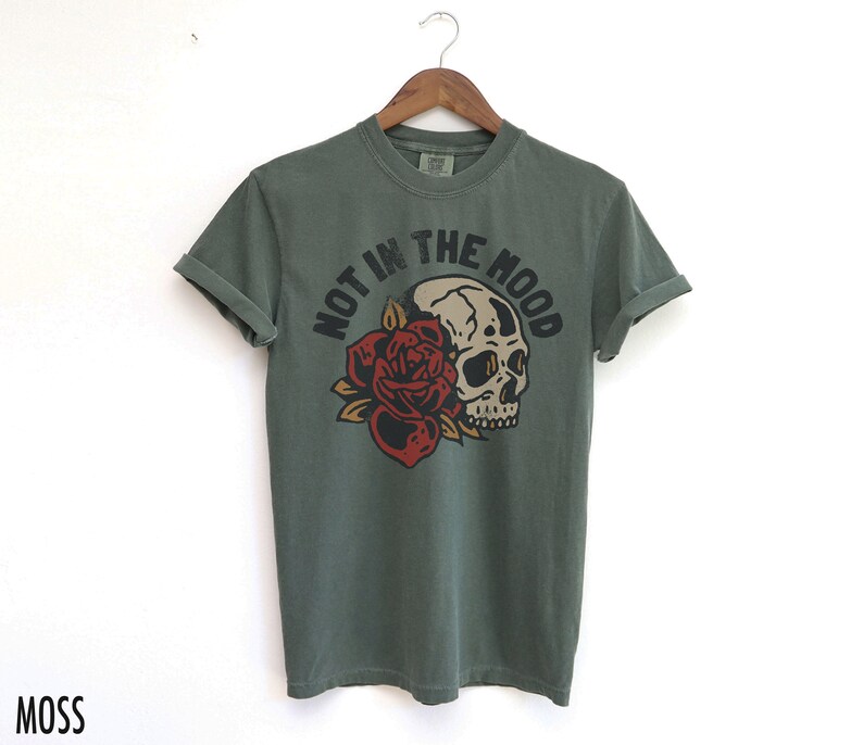 May include: A green t-shirt with a skull and rose graphic and the text "Not in the mood".
