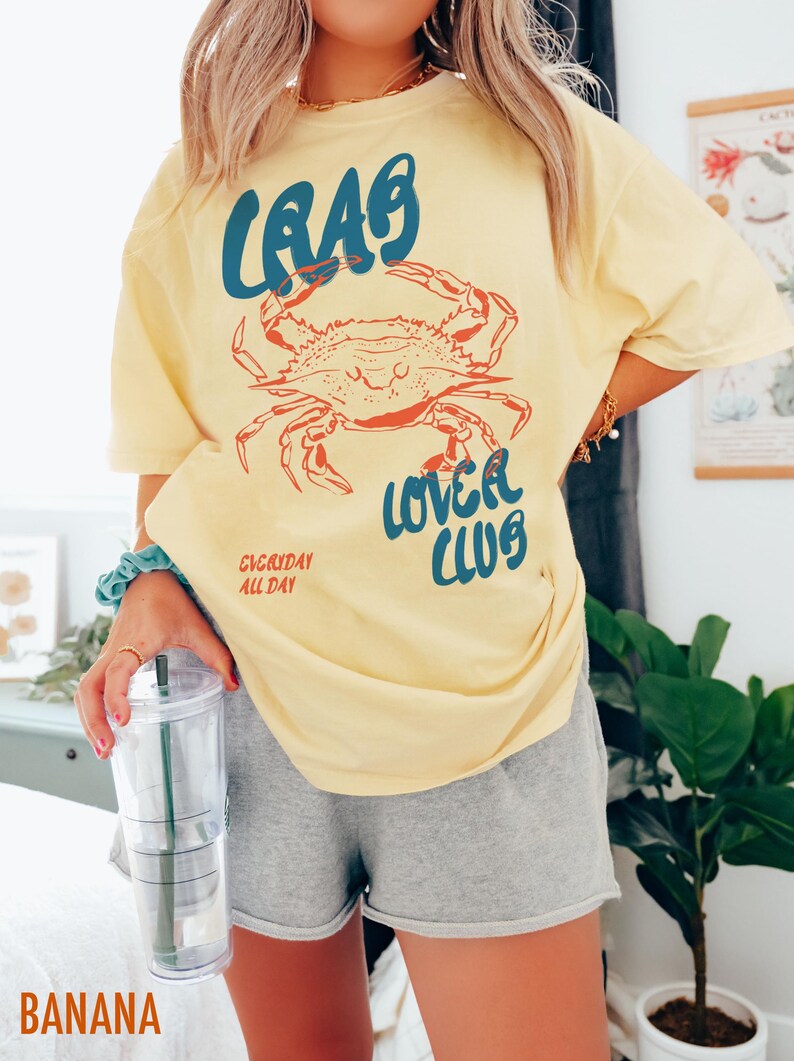 May include: A yellow t-shirt with a blue and red crab graphic and the text "Crab Lover Club" and "Everyday All Day".